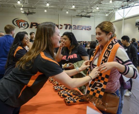staff member giving student a Tiger scarf